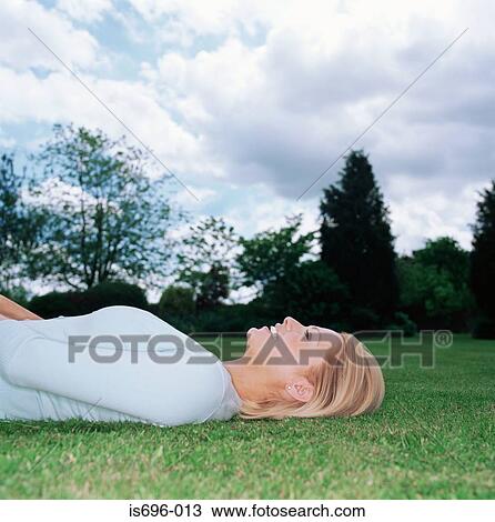 Stock Image - Blond woman lying on grass. Fotosearch