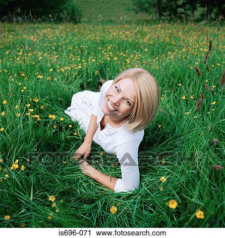 Blond woman lying on grass View Large Photo Image Stock Image - Blond woman lying on grass. Fotosearch