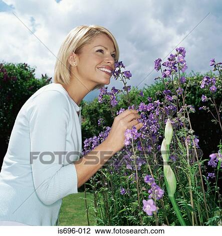 Blond woman smelling flowers View Large Photo Image Stock Image - Blond woman smelling flowers. Fotosearch
