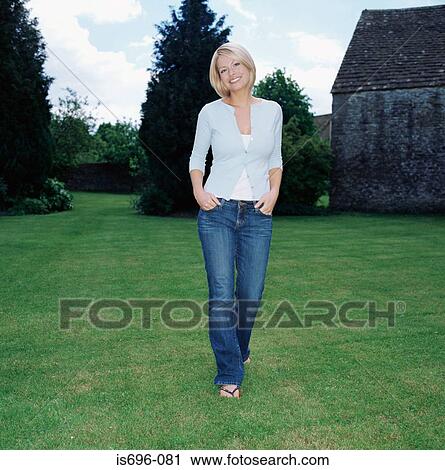 Stock Image - Blond woman walking in garden. Fotosearch