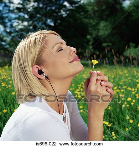 Woman in headphones smelling daisy View Large Photo Image Stock Image - Woman in headphones smelling daisy. Fotosearch