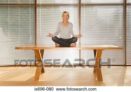 Woman meditating on table View Large Photo Image Stock Image - Woman meditating on table. Fotosearch