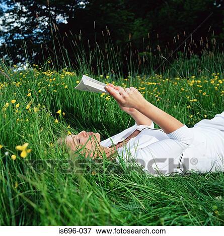Woman reading book on grass View Large Photo Image Stock Photo - Woman reading book on grass. Fotosearch