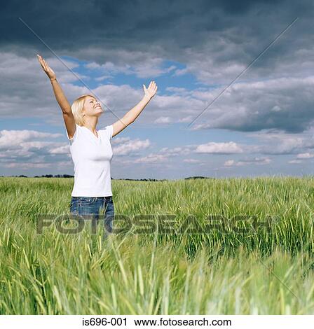 Stock Image - Woman with open arms in field. Fotosearch