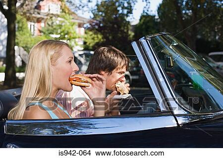 Couple eating burgers in convertible View Large Photo Image Picture - Couple eating burgers in convertible. Fotosearch