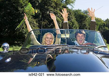 Couple in convertible with arms raised View Large Photo Image Stock Image - Couple in convertible with arms raised. Fotosearch