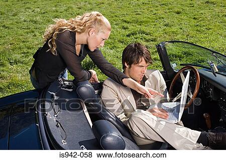 Stock Photo - Couple in convertible with laptop. Fotosearch