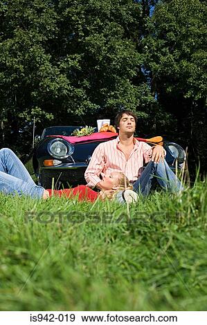 Stock Photo - Couple in field by car. Fotosearch