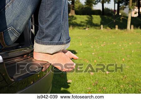 Feet of man sitting on car View Large Photo Image Stock Photo - Feet of man sitting on car. Fotosearch