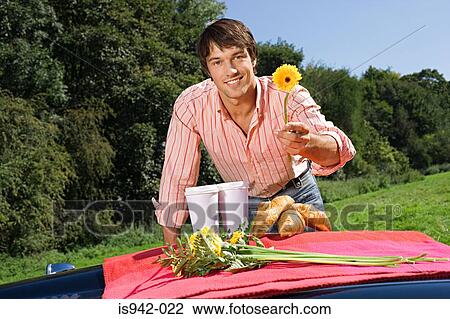 Handsome young gentleman offering flower View Large Photo Image Stock Image - Handsome young gentleman offering flower. Fotosearch