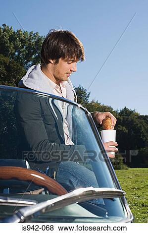 Man having breakfast by convertible View Large Photo Image Stock Photo - Man having breakfast by convertible. Fotosearch