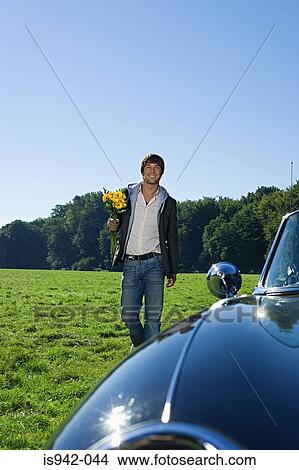 Man holding flowers in field View Large Photo Image Picture - Man holding flowers in field. Fotosearch