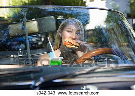 Woman eating hamburger in convertible View Large Photo Image Stock Image - Woman eating hamburger in convertible. Fotosearch