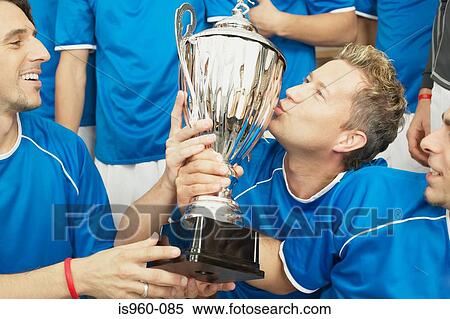 Stock Photography - Footballer kissing a trophy. Fotosearch