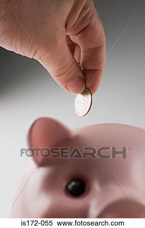 Stock Photography - Putting money in piggy bank. Fotosearch
