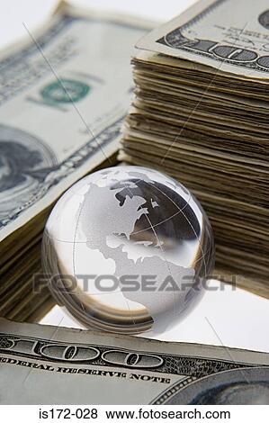 Stock Photo - Silver globe and stacks of dollars. Fotosearch