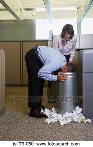 Stock Image - Businessman being sick in rubbish bin. Fotosearch