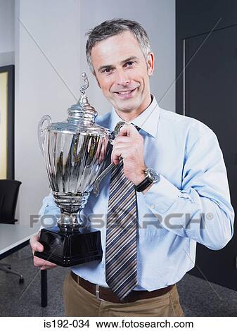 Businessman holding a trophy View Large Photo Image Picture - Businessman holding a trophy. Fotosearch