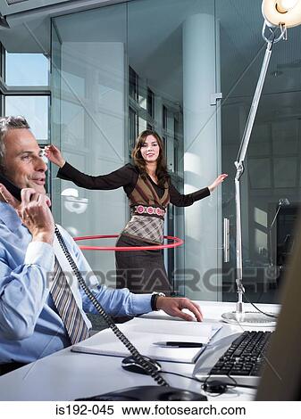 Stock Photography - Office worker playing with hula hoop. Fotosearch