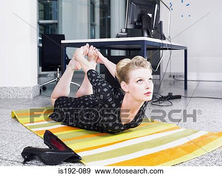 Stock Photo - Woman doing yoga in office. Fotosearch