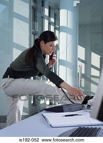 Stock Image - Woman on the telephone and stretching. Fotosearch