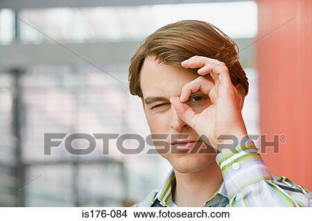 Picture - Man looking through curled fingers. Fotosearch