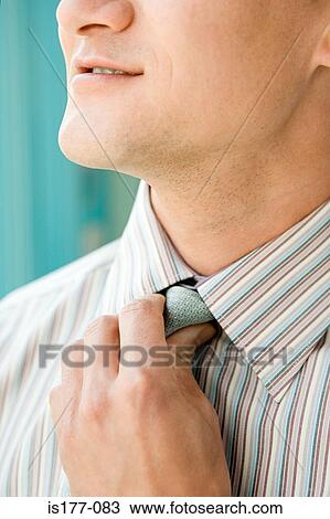 Stock Image - Man adjusting tie. Fotosearch