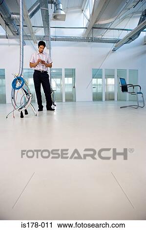 Man standing in sparse office View Large Photo Image Stock Image - Man standing in sparse office. Fotosearch