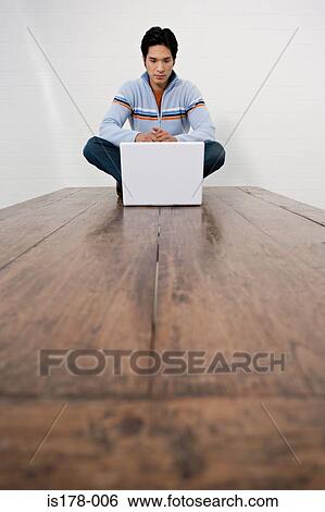 Man with laptop sitting on table View Large Photo Image Stock Photograph - Man with laptop sitting on table. Fotosearch