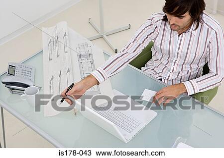 Young man at his desk View Large Photo Image Stock Image - Young man at his desk. Fotosearch