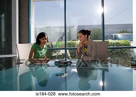 Businesswomen listening to speakerphone View Large Photo Image Stock Photo - Businesswomen listening to speakerphone. Fotosearch