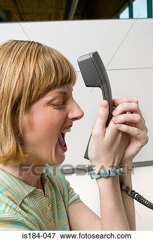 Stock Photo - Office worker shouting into telephone. Fotosearch