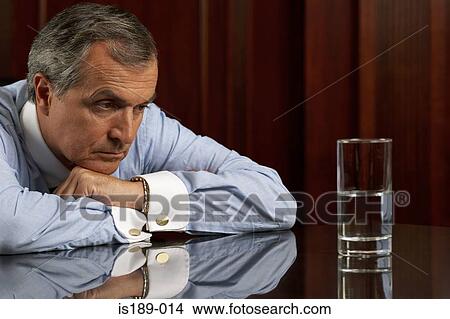 Businessman looking pessimistically at a glass of water View Large Photo Image Picture - Businessman looking pessimistically at a glass of water. Fotosearch