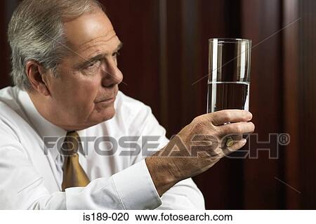 Businessman looking thoughtfully at glass of water View Large Photo Image Stock Image - Businessman looking thoughtfully at glass of water. Fotosearch