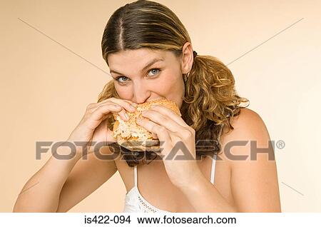 Woman eating a burger View Large Photo Image Picture - Woman eating a burger. Fotosearch