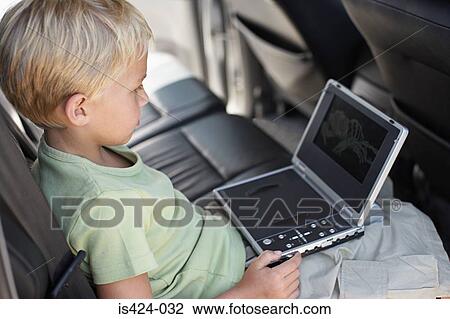 Stock Image - Boy sat in car with portable dvd player. Fotosearch