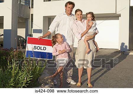 Family stood outside house holding sold sign View Large Photo Image Stock Photo - Family stood outside house holding sold sign. Fotosearch