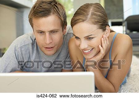 Stock Image - Mid adult couple using laptop. Fotosearch
