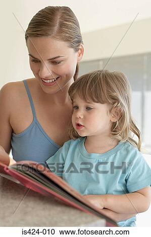 Mother helping her daughter to read View Large Photo Image Stock Image - Mother helping her daughter to read. Fotosearch