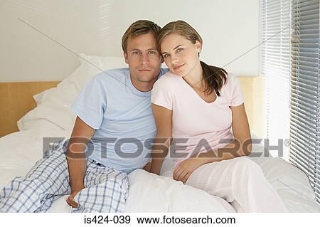 Portrait of mid adult couple sat on their bed View Large Photo Image Stock Photo - Portrait of mid adult couple sat on their bed. Fotosearch