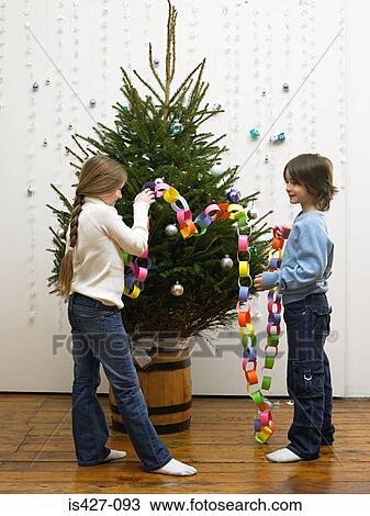 Stock Image - Brother and sister decorating christmas tree. Fotosearch