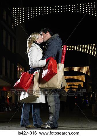 Couple kissing whilst christmas shopping View Large Photo Image Stock Photograph - Couple kissing whilst christmas shopping. Fotosearch