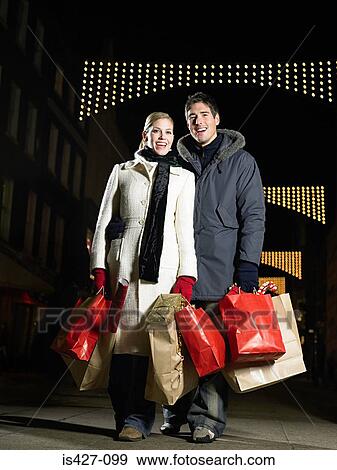 Mid adult couple christmas shopping View Large Photo Image Stock Photo - Mid adult couple christmas shopping. Fotosearch