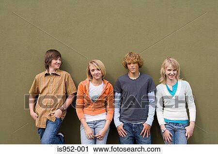 Stock Image - Four teenagers leaning against wall. Fotosearch