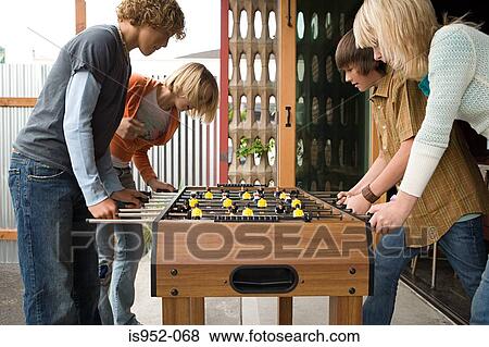 Stock Photo - Four teenagers playing table football. Fotosearch