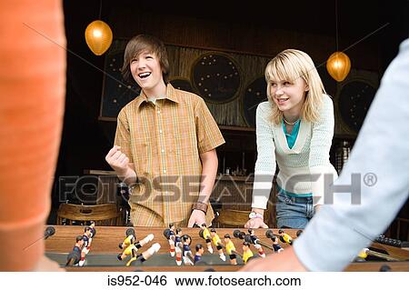 Stock Photograph - Four teenagers playing table football. Fotosearch