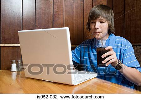 Teenage boy working on laptop in cafe View Large Photo Image Stock Image - Teenage boy working on laptop in cafe. Fotosearch