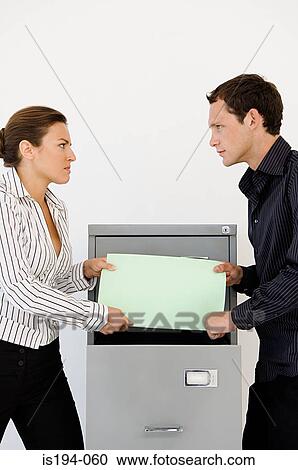 Stock Image - Businessman and businesswoman fighting over file. Fotosearch
