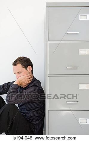 Businessman hiding behind filing cabinet View Large Photo Image Stock Photograph - Businessman hiding behind filing cabinet. Fotosearch