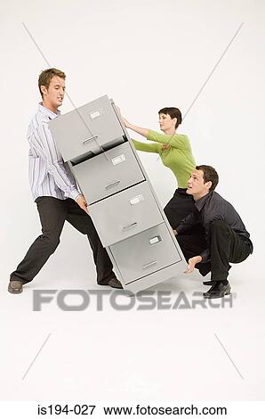 Stock Photo - Three office workers lifting heavy filing cabinet. Fotosearch